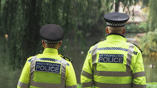 Two male police officers walking next to a canal